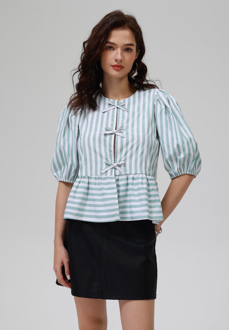Gestreifte Peplum-Bluse in Hellgrün und Weiß, mit kurzen Puffärmeln, rundem Ausschnitt und dekorativen Schleifenakzenten auf der Vorderseite.