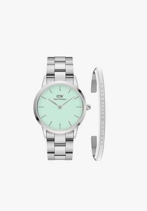 Sidabrinis nerūdijančio plieno laikrodis su mėtų žalios spalvos ciferblatu, turintis minimalistiškus valandų žymeklius ir rodykles. Pridedamas atskiras graviruotas sidabrinis apyrankis.