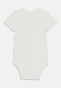 Bodysuit pour bébé à manches courtes, de couleur crème, fabriqué en coton doux, avec un col rond et une fermeture à pression au bas. Texture simple et lisse.