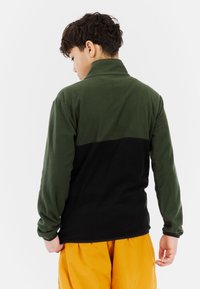 Fleece-Pullover mit hohem Kragen, in der oberen Sektion dunkelgrün und in der unteren Sektion schwarz. Weicher Stoff und lange Ärmel.