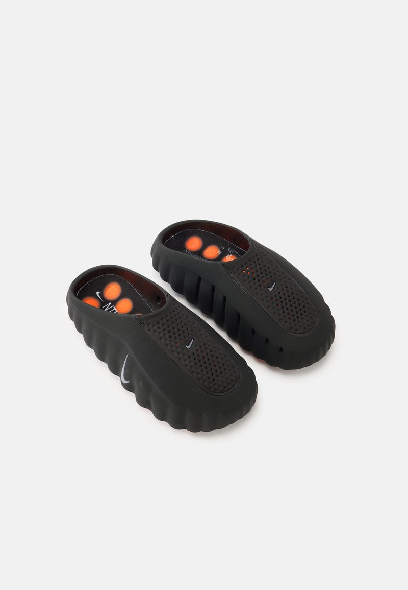 Μαύρα παπούτσια χωρίς κορδόνια από καουτσούκ με υφή στην επάνω επιφάνεια, οπές για αερισμό και επενδεδυμένο εσωτερικό με πορτοκαλί λεπτομέρειες.