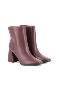 Par de botas de cuero de color malva oscuro, de altura hasta el tobillo, con tacones cuadrados y acabado suave, mostradas sobre un fondo blanco.