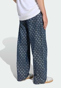 Modré široké nohavice s listovým vzorom, vyrobené z denimu s jemnou textúrou. Nosili sa s bielymi teniskami a jednoduchým bielym tričkom.