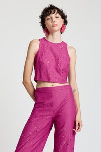 Fuchsia lace crop top with a round neckline paired with matching wide-leg pants, featuring intricate floral patterns and cut-out details.