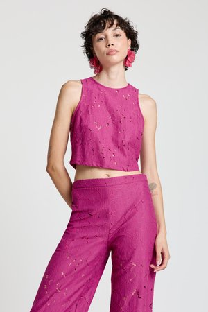 Fuchsia-farbenes Spitzen-Cropped-Top mit rundem Ausschnitt, kombiniert mit passenden weiten Hosen, die filigrane Blumenmuster und Ausschnittdetails aufweisen.