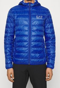 Blaues Puffer-Jackett mit Kapuze, Reißverschluss vorne und Logodetails. Verfügt über ein gestepptes Design und glänzendes, synthetisches Material zur Isolation.