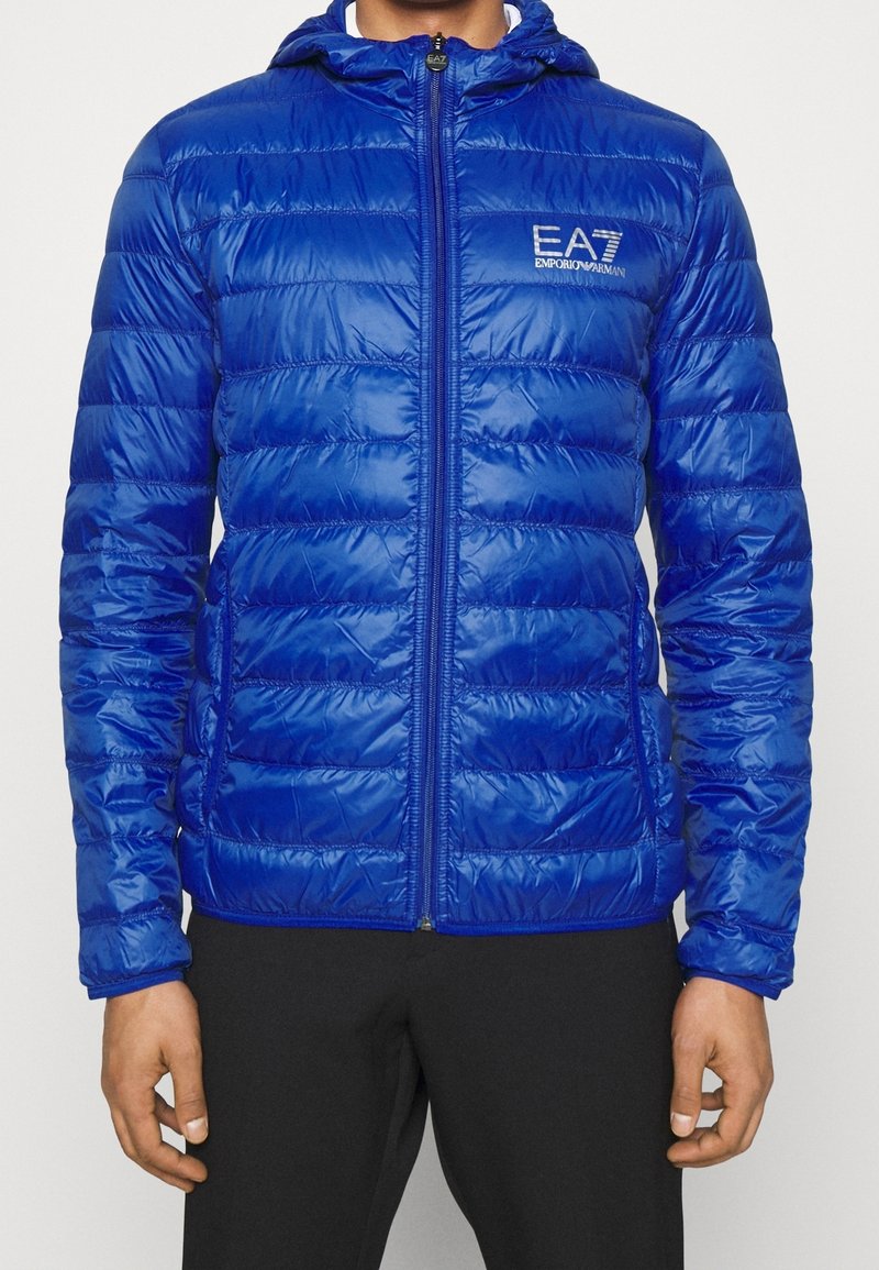 Blaues Puffer-Jackett mit Kapuze, Reißverschluss vorne und Logodetails. Verfügt über ein gestepptes Design und glänzendes, synthetisches Material zur Isolation.