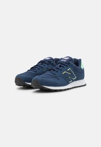Pair of navy blue New Balance 500 sneakers with black soles, white midsoles, and light green accents on a white background.