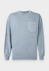 Μπλε μπλουζάκι με μακριά μανίκια από απαλό βαμβάκι, με στρογγυλή λαιμόκοψη και τσέπη στο στήθος με διακριτική ραφή.