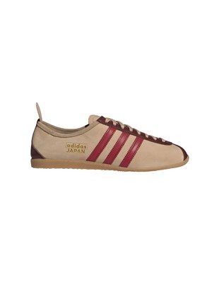 Zapatillas Adidas en ante beige con rayas burdeos y suela de goma. Presentan un logo en el lateral y cierre con cordones planos.