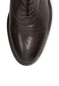 Brązowe skórzane buty wizytowe z okrągłym nosem, misternymi perforacjami w stylu brogue oraz gładkim wykończeniem. Posiadają klasyczny system sznurowania.