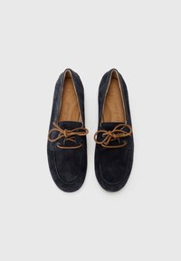 Navy blue suede loafers with a rounded toe, brown laces, and tan insoles featuring embossed text. Smooth texture and streamlined design.
