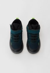 Dunkelblaue Sportschuhe mit schwarzen Akzenten, Textilobermaterial, Gummisohle und Klettverschluss. Neon-grüne Highlights auf der Zunge und den Seiten.