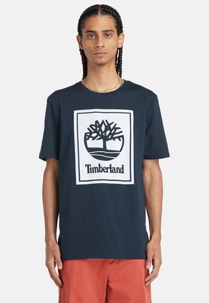 T-shirt en coton bleu marine avec un logo Timberland imprimé en blanc et un design d'arbre au centre, à manches courtes et col rond.