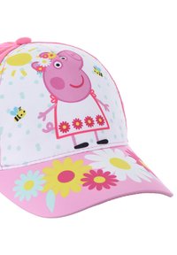 Gorra de béisbol rosa con un cerdo de dibujos animados vestido con un vestido blanco con detalles de flores, rodeado de abejas y puntos de colores sobre un fondo blanco.