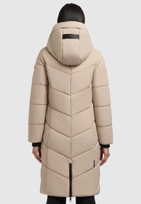 Béžová vatovaná bunda so vzorom šípok, kapucňou a predným zipsom. Textúrovaná látka, dĺžka po kolená a elastické manžety.