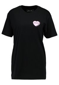 Czarna bawełniana koszulka z krótkim rękawem, z różową łatką w kształcie serca i napisem "MEMES" na lewej stronie klatki piersiowej. Klasyczny dekolt typu crew.