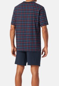 Men's short-sleeve shirt featuring a navy plaid pattern with red and blue lines, paired with navy shorts. Cotton material, relaxed fit.