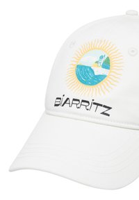 White cotton cap featuring an embroidered circular design with a sun, waves, and a lighthouse. "BIARRITZ" is printed in bold black letters below.