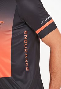 Zwart en oranje sporttrui met een gradient ontwerp, voorzien van de tekst "ENDURANCE" op de zijkant en contrasterende oranje accenten op de mouwen.