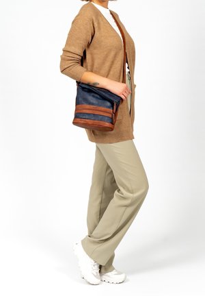 Umhängetasche in Marineblau mit braunen Lederakzenten, Reißverschlussfächern, weicher Textur und vielseitigem Design. Geeignet für den täglichen Gebrauch.