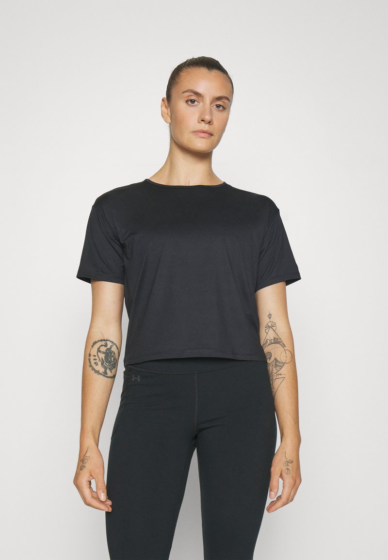 Svart croppet t-skjorte laget av glatt stoff, med rund hals og korte ermer, parret med svarte tettsittende leggings.