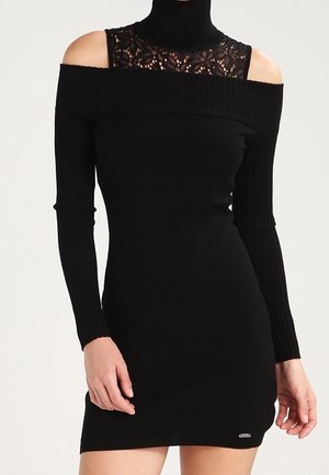 Czarna dopasowana sukienka dzianinowa z wycięciami na ramionach, długimi prążkowanymi rękawami, wysoką koronkową wstawką oraz małym metalicznym logo przy brzegu.