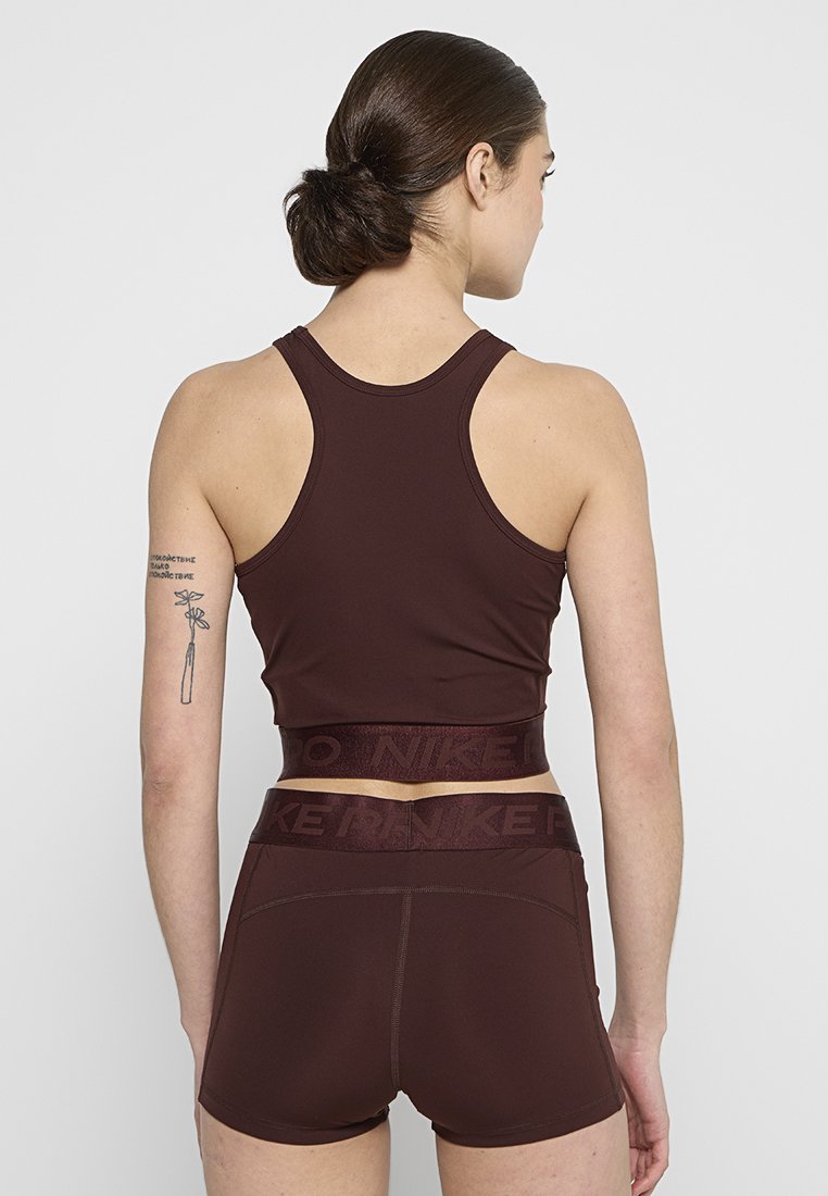 Haut de sport bordeaux à crop et shorts, en tissu lisse. Comprend un logo de marque sur la ceinture et un design dos nageur.