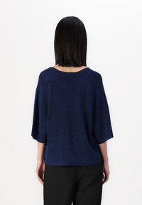 Marinblå, löst sittande tröja med korta ärmar och bred halsringning, som har en subtil glittrande textur och rak fålldesign.