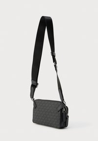 Μαύρο τσαντάκι χιαστί από υφασμα με σχέδια, με φερμουάρ, ρυθμιζόμενο λουράκι και ασημένιες μεταλλικές λεπτομέρειες. Συμπαγές και ορθογώνιο σχέδιο.