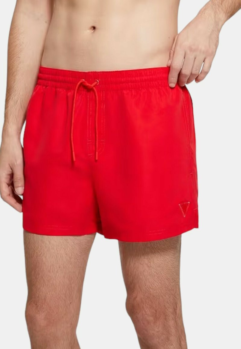 Costumi da bagno rossi con cintura elasticizzata e coulisse, dotati di parte anteriore piatta, tasche laterali e un logo decorativo sull'orlo inferiore.