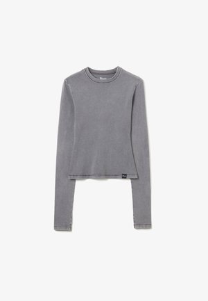 Grijze langslijfshemd, cropped ontwerp, lichtgewicht stof, minimale naden, ronde halslijn en een klein label aan de onderkant links.