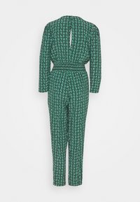 Jumpsuit à fleurs vert avec des manches longues, taille smockée et détail de dos en forme de clé, arborant un motif de petites fleurs blanches.