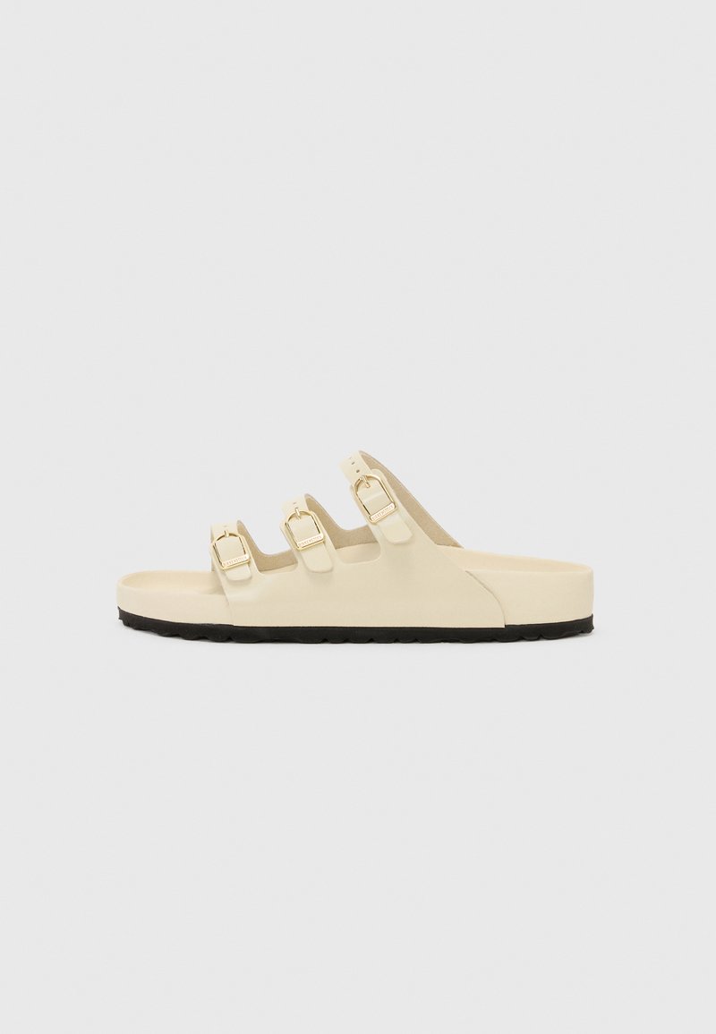 Beige színű csúszós papucs három állítható pánttal, arany csattal és texturált fekete gumi talppal. Simább anyag és minimalista design.
