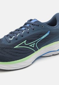 Scarpe da corsa in rete blu scuro con accenti verdi e blu chiaro. Presentano una suola ammortizzata e un design testurizzato per traspirabilità e supporto.