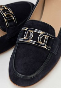 Marineblaue Wildleder-Lederschuhe mit einem schwarzen und goldenen Metallkettenakzent, Rundkopf-Form und strukturierten Details entlang der Ränder.