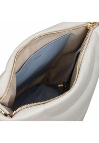 Weicher, beiger Lederhandtaschen-Innenraum mit goldenem Reißverschluss, ausgestattet mit mehreren Taschen in hellblauen und beigen Innenfutter, und zeigt einen sauberen, organisierten Raum.