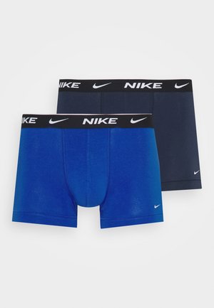 Kaks paari meeste bokserite aluspükse: üks sinine ja teine tume tumesinine, mõlemal must elastne vöökoht, millel on valge Nike bränding.