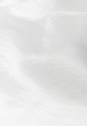 Tissu blanc texturé avec des vagues douces et des variations subtiles, offrant une qualité légère et aérée. Pas de motifs ou de matériaux visibles.