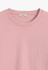 Różowa koszulka na krótki rękaw wykonana z bawełny, z okrągłym dekoltem, z metką z napisem "ATLANTIC" i rozmiarem "S". Gładka tekstura, minimalistyczny design.