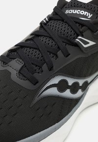 Scarpa da ginnastica nera con tomaia in rete, lacci piatti e accenti argento. Presenta un motivo testurizzato e una suola intermedia bianca. Logo sulla linguetta.