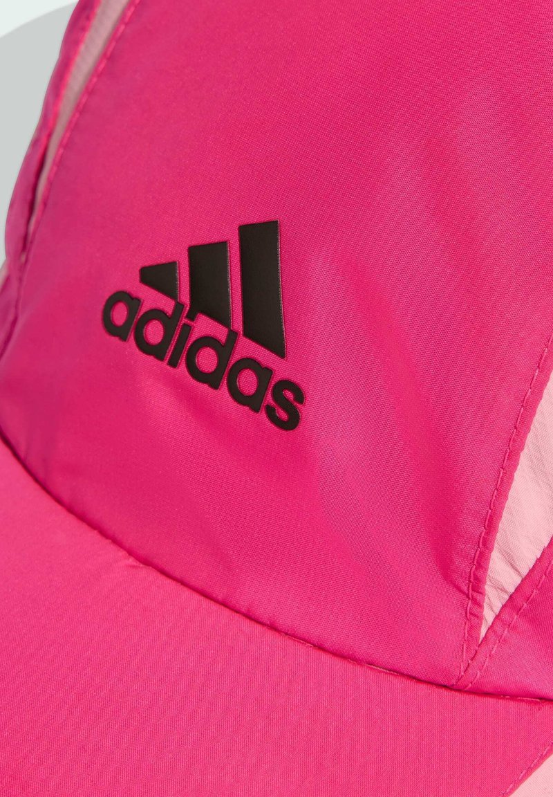 Pink Adidas cap made of smooth fabric with a black logo, featuring a curved visor and panel design, detailing subtle texture variations.