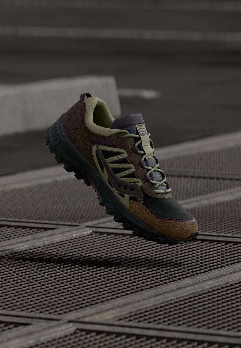 Pánská běžecká obuv do terénu v tmavě zelené a hnědé barvě. Vybavena texturovanou černou gumovou podrážkou, šněrováním a podpůrnou svrchní částí s vícemi barvami.