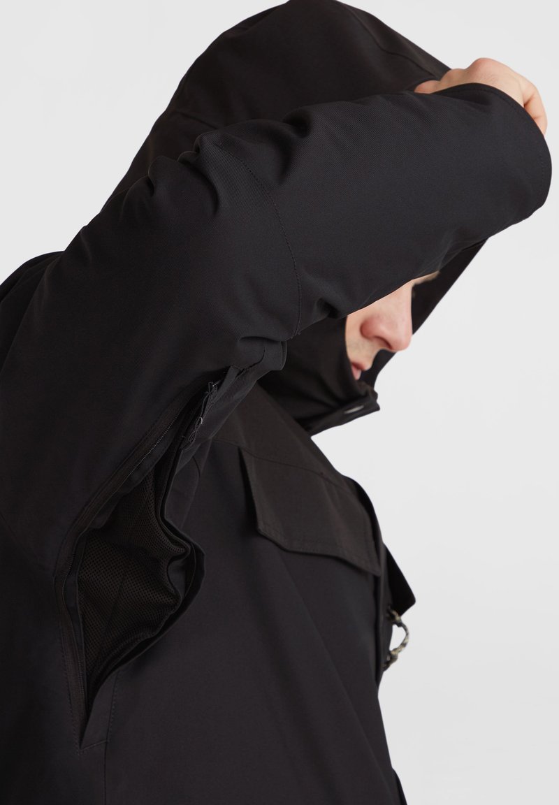 Czarna kurtka z kapturem, z zamkiem błyskawicznym i siateczkowym wykończeniem. Posiada strukturalny design z charakterystycznym krojem ramion i płaską kieszenią.