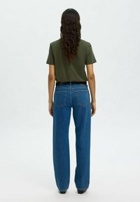 Groene katoenen t-shirt en hoge taille blauwe denim wijde jeans. De jeans hebben twee achterzakken en een knoopsluiting.
