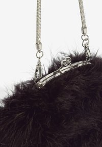 Juodas dirbtinio kailio rankinys su sidabriniu metaliniu užsegimu. Yra grandinėlė su akmenukais ir tekstūruota apdaila.