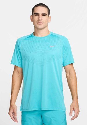 Camiseta deportiva Nike de color turquesa, con mangas cortas, cuello redondo, diseño texturizado en la parte frontal superior y pequeño logo en el pecho.