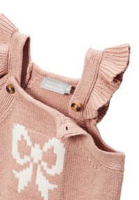 Vêtement tricoté rose avec des bretelles froncées, arborant un motif de nœud blanc. Comprend des boutons en bois et une étiquette en tissu à l'intérieur.