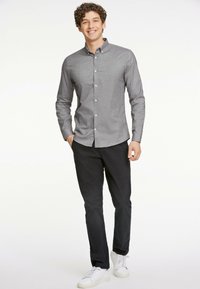 Camicia grigia button-up con una vestibilità su misura, abbinata a pantaloni neri e sneakers bianche. La camicia ha il colletto ed è texturizzata.