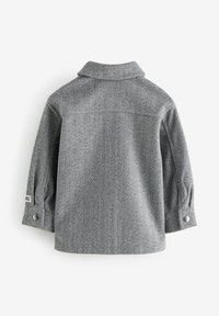 Veste grise à motif chevrons, manches longues, col et poignets boutonnés, vue de dos sur fond blanc.